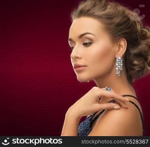 jewelry and beauty concept - beautiful woman in evening dress wearing diamond earrings and ring