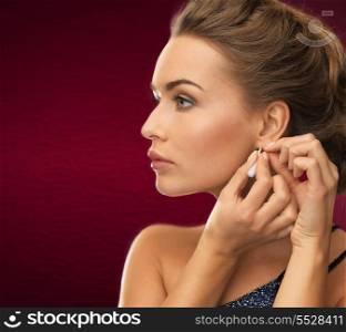 jewelry and beauty concept - close up of beautiful woman wearing shiny diamond earrings