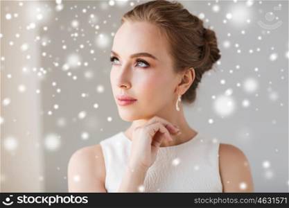jewelry, luxury, christmas, holidays and people concept - beautiful woman in white dress with diamond earring over snow