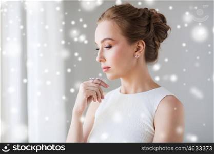 jewelry, luxury, christmas, holidays and people concept - beautiful woman in white dress with diamond earring and ring over snow