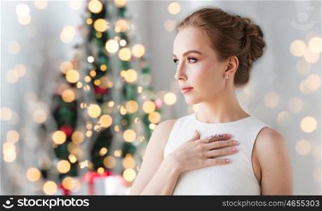 jewelry, luxury, christmas, holidays and people concept - smiling woman in white dress with diamond earring and ring over lights background