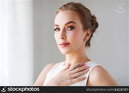 jewelry, luxury, wedding and people concept - smiling woman in white dress with diamond earring and ring