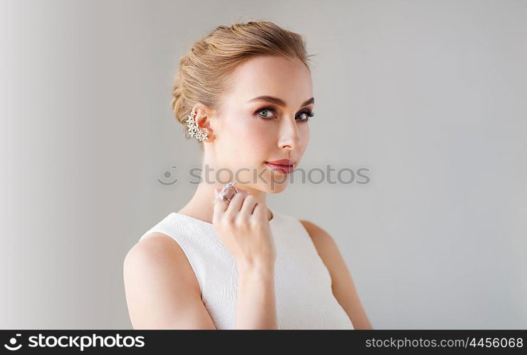 jewelry, luxury, wedding and people concept - smiling woman in white dress with diamond earring and ring