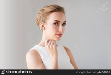 jewelry, luxury, wedding and people concept - smiling woman in white dress with diamond earring and ring