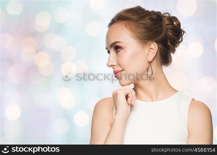 jewelry, luxury, wedding and people concept - smiling woman in white dress wearing pearl earrings over blue holidays lights background