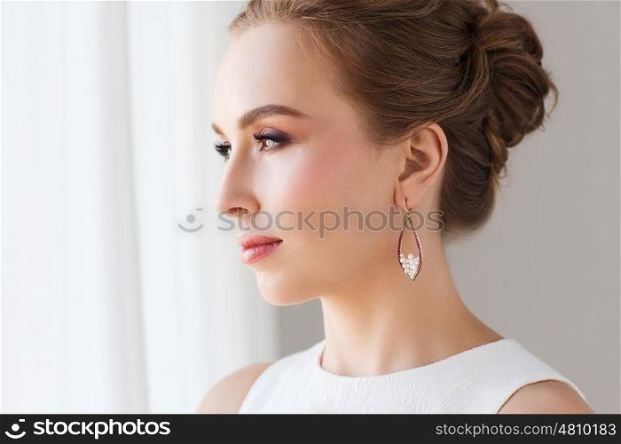 jewelry, luxury, wedding and people concept - smiling woman in white dress wearing pearl earring