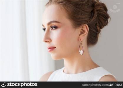 jewelry, luxury, wedding and people concept - smiling woman in white dress wearing pearl earring