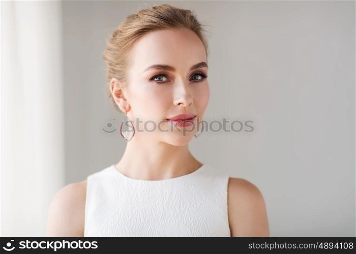 jewelry, luxury, wedding and people concept - smiling woman in white dress wearing pearl earrings
