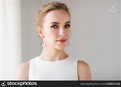 jewelry, luxury, wedding and people concept - smiling woman in white dress wearing pearl earrings