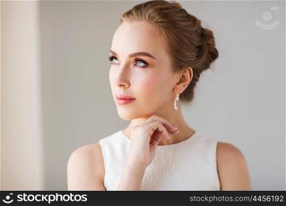 jewelry, luxury, wedding and people concept - smiling woman in white dress with diamond earring