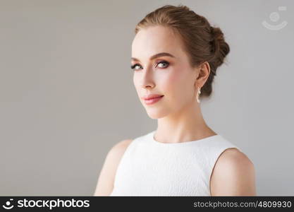 jewelry, luxury, wedding and people concept - smiling woman in white dress with diamond earring