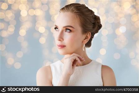 jewelry, luxury, wedding, holidays and people concept - beautiful woman in white dress with diamond earring