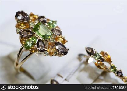 jewelry retail store showcase displaying white gold ring with precious gemstones. ring with emeralds, topazes, citrenes. close up