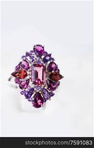 jewelry retail store showcase displaying white gold ring with precious gemstones. ring with amethysts, rubies, turmalines. close up