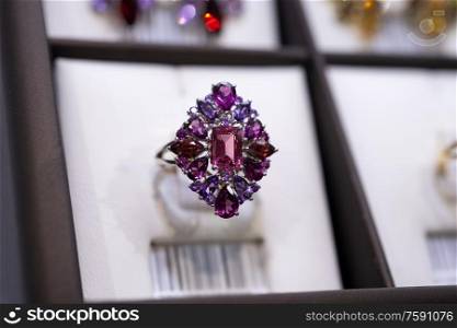 jewelry retail store showcase displaying white gold ring with precious gemstones. ring with amethysts, turmakins. close up