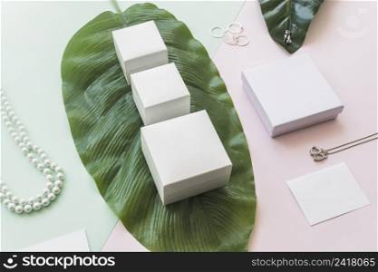 jewelry with white boxes green leaf paper backdrop