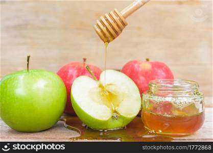 Jewish holiday, Apple Rosh Hashanah, the photo have honey in jar and drop honey on green apples on wooden background