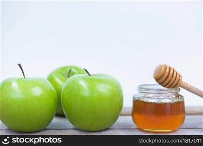 Jewish holiday, Apples Rosh Hashanah on the photo have honey in jar have green apples on wooden with white background