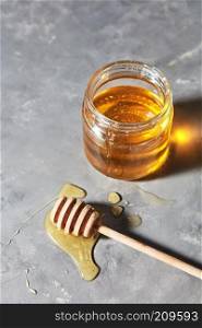 Jewish holiday Rosh Hashanah background with sweet organic honey on a gray concrete background, copy space. Top view. Traditional useful sweetness.. A puddle of honey on the table with glass pot with natural organic dessert on a gray concrete table. Jewish New Year healthy holiday .