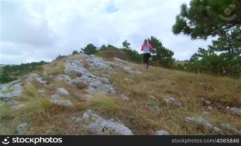 JIB CRANE: Fit young woman trail running in the mountains