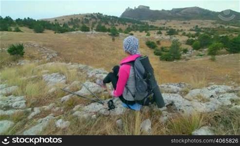 JIB CRANE: Woman hiker hiking mountain highlands relaxing on edge of cliff rear view, Ai-Petri plateau, Crimea