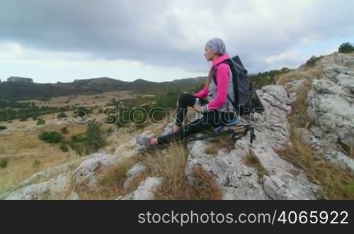 JIB CRANE: Woman hiker with backpack and trekking poles relaxing on top of mountain plateau Ai-Petri looking away