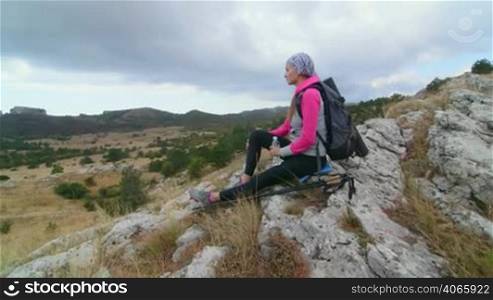 JIB CRANE: Woman hiker with backpack and trekking poles relaxing on top of mountain plateau Ai-Petri looking away