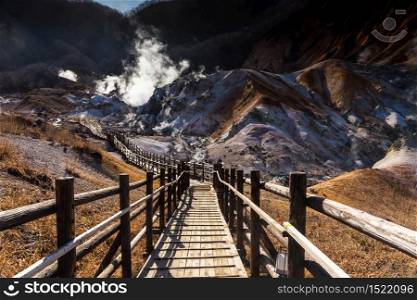 Jigokudani hell valley wooden walking path in morning in sunny day at spring, Noboribetsu, Hokkaido, Japan. Famous natural travel destination with onsen bath in town.