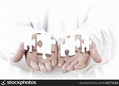 Jigsaw elements. Human hands with white pieces of puzzle