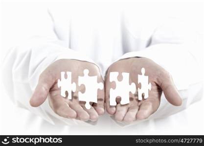 Jigsaw elements. Human hands with white pieces of puzzle
