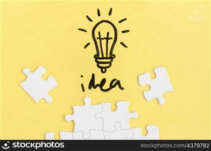 jigsaw puzzle light bulb with idea word yellow background