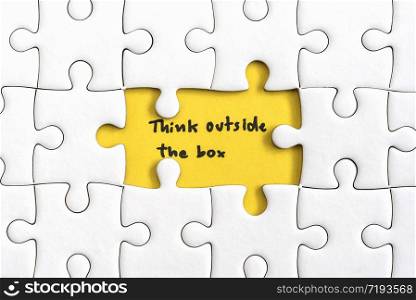 Jigsaw puzzle piece with two missing and hand writing letters word think outside the box. think outside the box quotes business concept