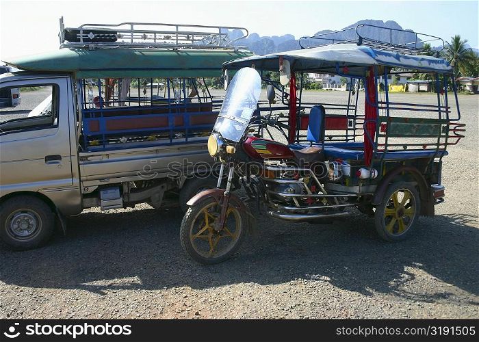 Jinrikisha and a truck parked at roadside, Vang Vieng, Laos