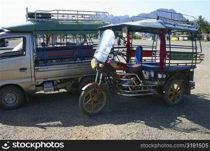 Jinrikisha and a truck parked at roadside, Vang Vieng, Laos
