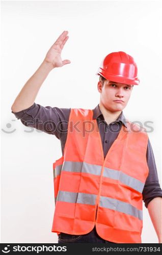 Job and work concept. Young male worker wearing safety vest and hard hat holding hand up. Repairman inspector at work.. Male worker in orange uniform with hand up.