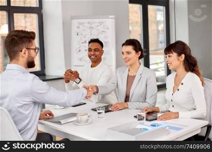 job, hiring and employment concept - international team of recruiters having interview with male employee and shaking hands at office. recruiters having interview with employee