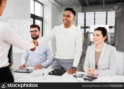 job, hiring and employment concept - international team of recruiters having interview with female employee and shaking hands at office. recruiters having interview with employee