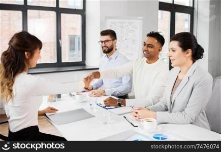 job, hiring and employment concept - international team of recruiters having interview with female employee and shaking hands at office. recruiters having interview with employee