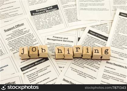 job hiring word on wood stamps place on classifieds ads of fake newspapers