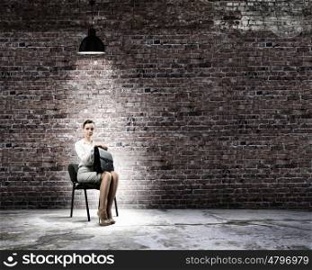 Job interview. Image of young businesswoman sitting on chair under spot of light