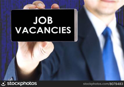 Job vacancies word on mobile phone screen in blurred young businessman hand and digital technology background