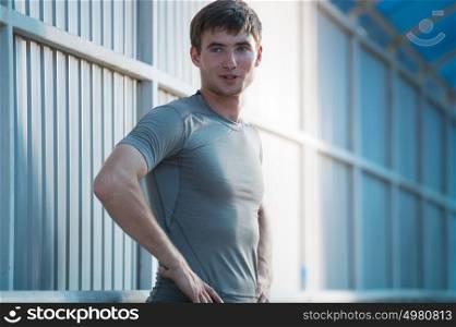 Jogger resting after running. Man runner taking a break during training outdoors in city. Young Caucasian male fitness model after work out.