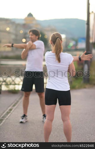 jogging couple warming up and stretching before morning running in the city