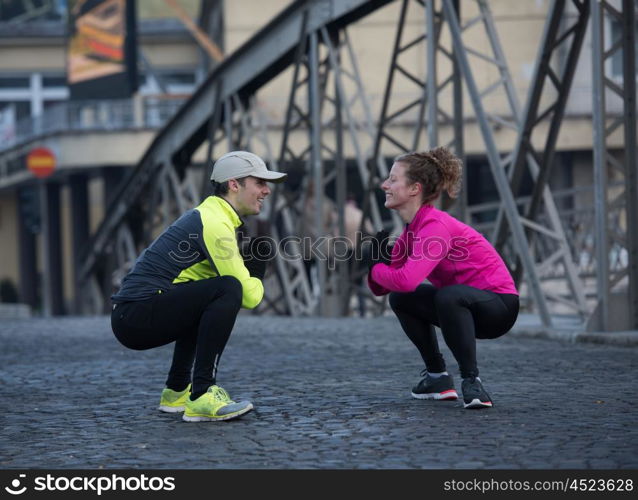 jogging couple warming up and stretching before morning running in the city