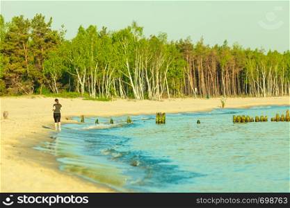Jogging during summertime, outdoor sports concept. Woman in sportswear running on beach near sea.. Woman in sportswear running through seaside