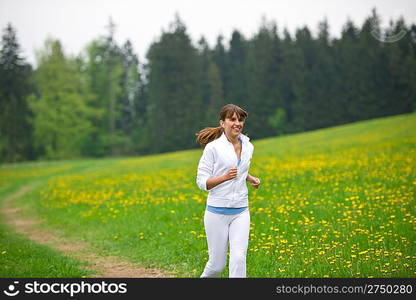 Jogging - sportive woman running in park with dandelion, listen to music with earbuds