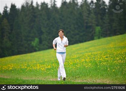 Jogging - sportive woman running in park with dandelion, listen to music with earbuds