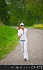 Jogging - sportive woman running on road in nature, listen to music with earbuds