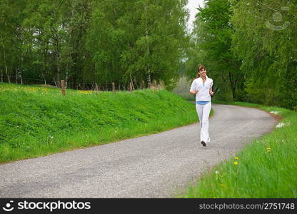 Jogging - sportive woman running on road in nature, listen to music with earbuds