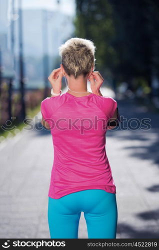 jogging woman setting music and running route on smart phone putting earphones before morning run